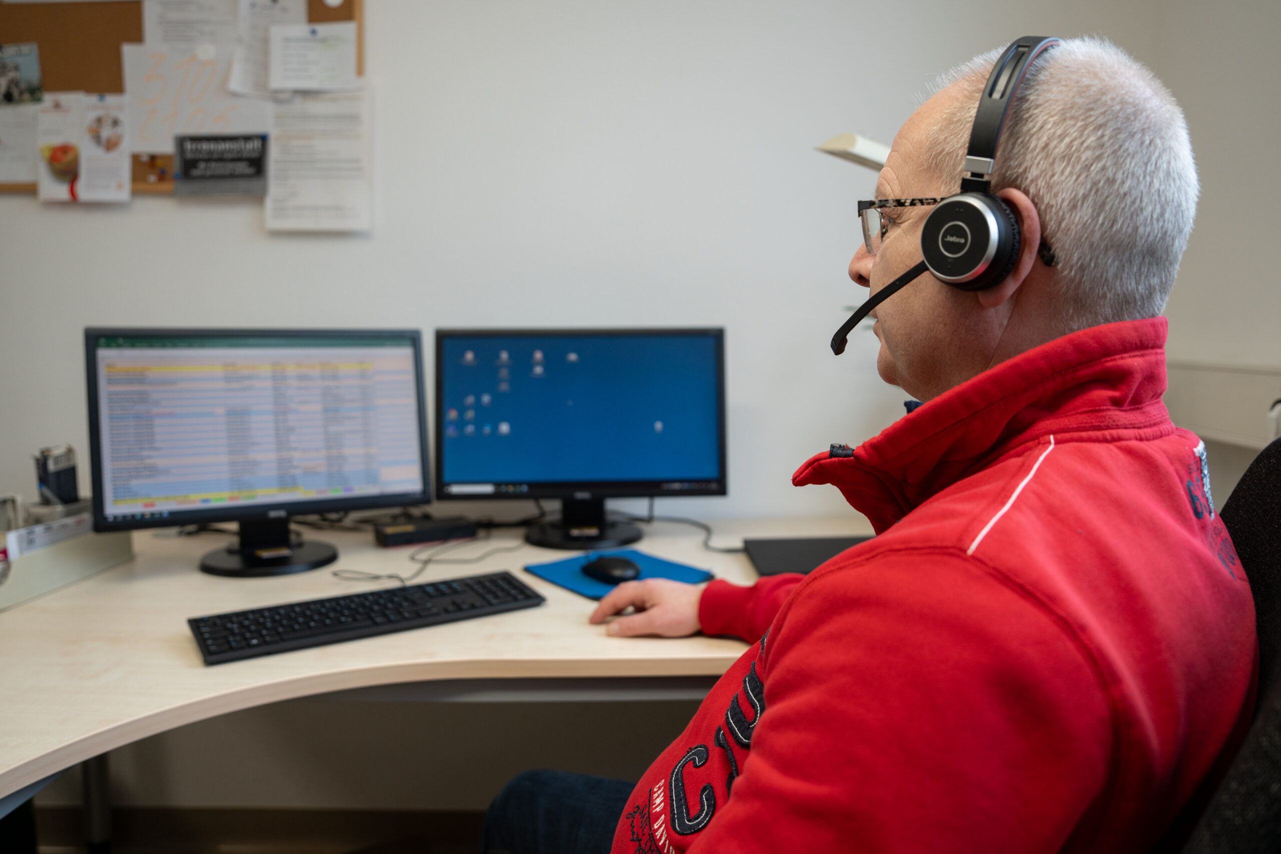 Ein Telefonist auf Arbeit mit Headset am Computer.